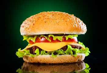 Image showing Tasty and appetizing hamburger on a darkly green