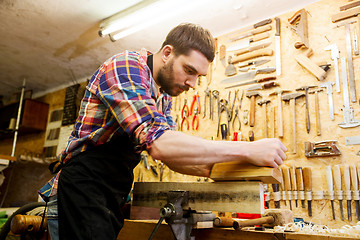 Image showing carpenter working with plane and wood at workshop