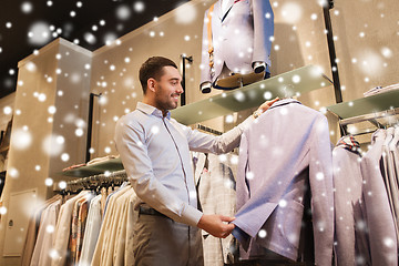 Image showing happy young man choosing clothes in clothing store