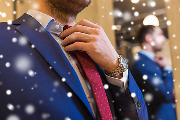 Image showing close up of man trying tie on at clothing store