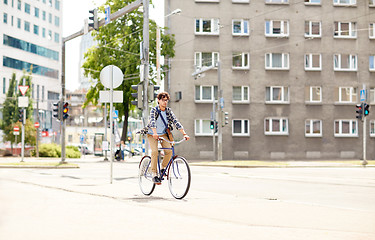 Image showing young hipster man with bag riding fixed gear bike