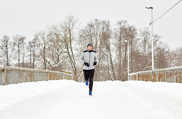 Image showing man running along snow covered winter bridge road