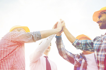 Image showing close up of builders in hardhats making high five