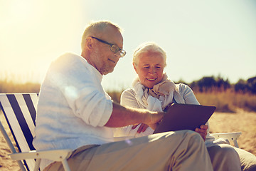 Image showing happy senior couple with tablet pc on summer beach