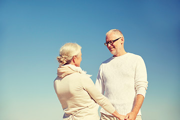 Image showing happy senior couple holding hands outdoors