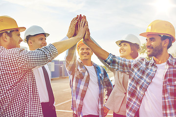 Image showing close up of builders in hardhats making high five