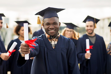 Image showing happy students in mortar boards with diplomas