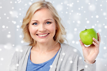Image showing happy middle aged woman with green apple at home