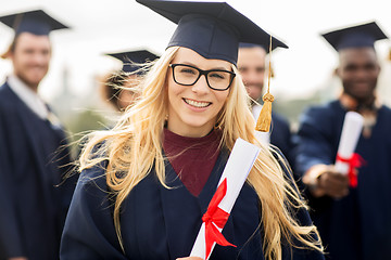 Image showing happy students in mortar boards with diplomas