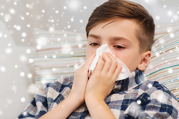 Image showing close up of ill boy lying in bed and blowing nose