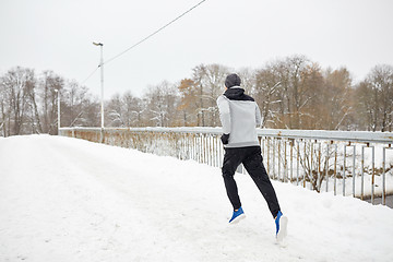 Image showing man running along snow covered winter bridge road