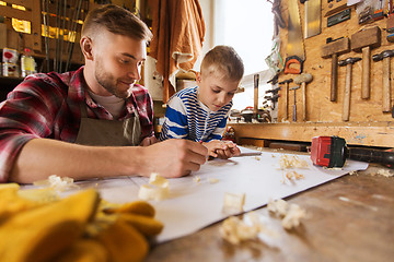 Image showing happy father and son with blueprint at workshop