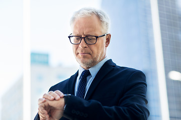 Image showing senior businessman checking time on his wristwatch