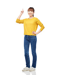 Image showing happy asian woman pointing finger up over white