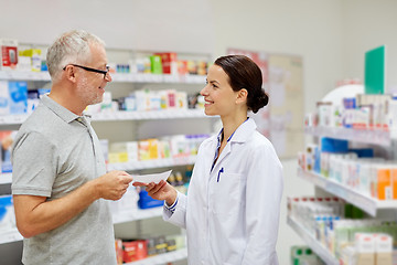 Image showing senior man giving prescription to pharmacist