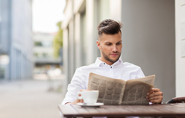 Image showing smiling man reading newspaper at city street cafe