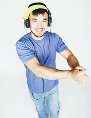 Image showing young asian man in hat and headphones listening music on white b