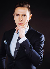 Image showing young pretty business man standing on black background, modern h