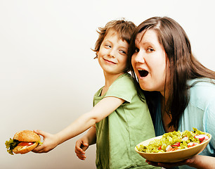 Image showing fat woman holding salad and little cute boy with hamburger on white background