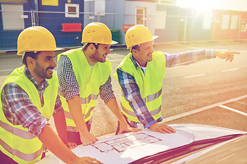 Image showing close up of builders with blueprint on car hood