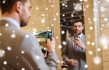 Image showing man in suit taking mirror selfie at clothing store