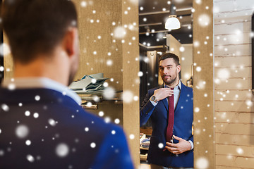 Image showing man trying tie on at mirror in clothing store