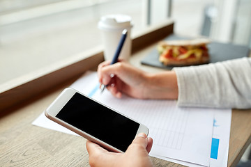 Image showing woman with smartphone and paper form at cafe