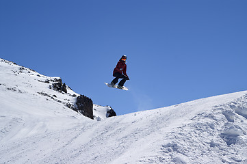 Image showing Snowboarder jumping in terrain park at ski resort on sun winter 