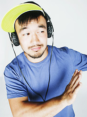 Image showing young asian man in hat and headphones listening music on white b