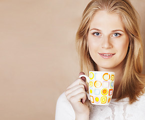 Image showing young cute blond girl drinking coffee close up on warm brown bac