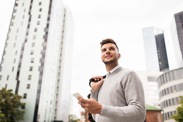 Image showing happy young man with bag and smartphone in city