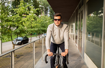 Image showing young man riding bicycle on city street