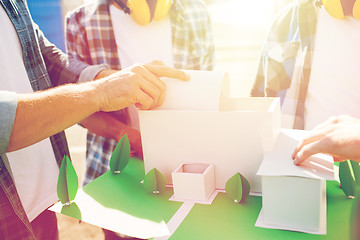 Image showing close up of builders with paper house model