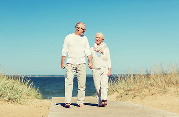 Image showing happy senior couple holding hands on summer beach