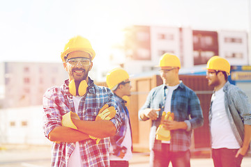 Image showing group of smiling builders in hardhats outdoors