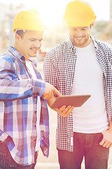Image showing smiling builders with tablet pc outdoors