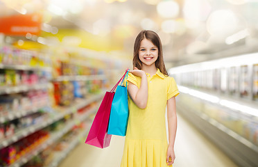 Image showing smiling girl with shopping bags over supermarket