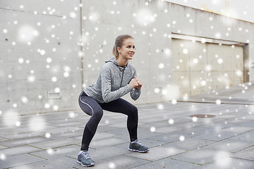 Image showing happy woman doing squats and exercising outdoors