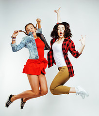 Image showing two pretty brunette and blonde teenage girl friends jumping happy smiling on white background, lifestyle people concept close up