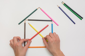 Image showing Women\'s hands are building a house from pencils