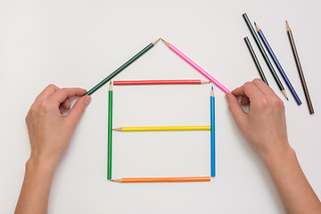 Image showing Hands close-up build a house on a piece of paper from the crayons