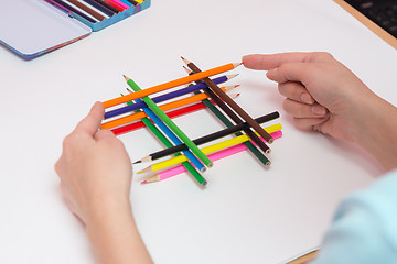 Image showing She builds a well of pencils on a sheet of white paper, close-up