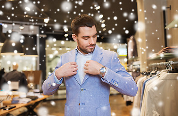 Image showing happy young man trying jacket on in clothing store