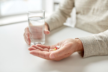 Image showing close up of old man hands with pills and water