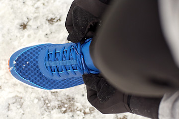 Image showing close up of man tying shoe lace in winter outdoors