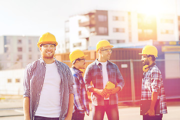 Image showing group of smiling builders in hardhats outdoors