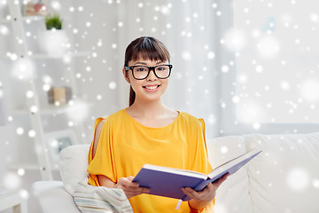 Image showing smiling young asian woman reading book at home