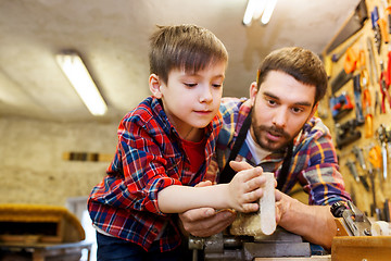 Image showing father and little son with wood plank at workshop