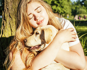 Image showing young attractive blond woman playing with her dog in green park at summer, lifestyle people concept