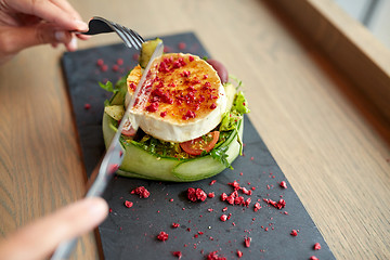 Image showing woman eating goat cheese salad at restaurant